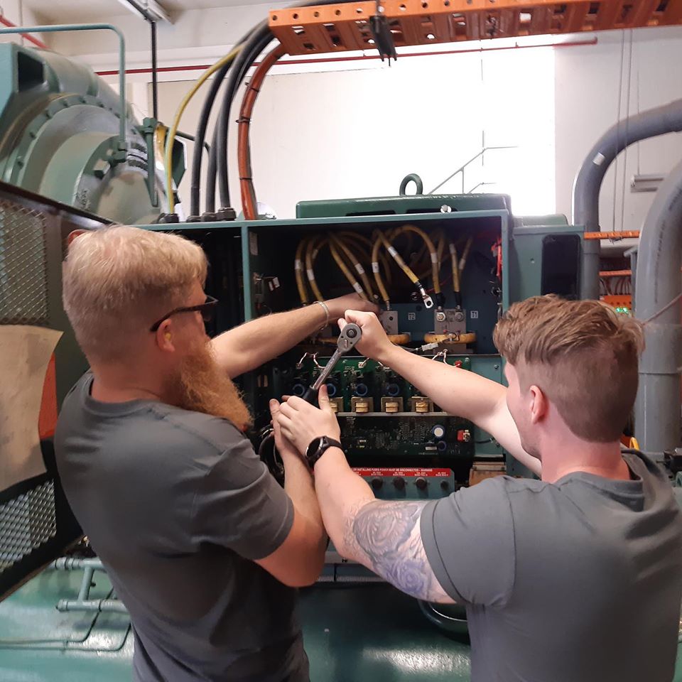 Two men tightening a bolt on a chiller installation