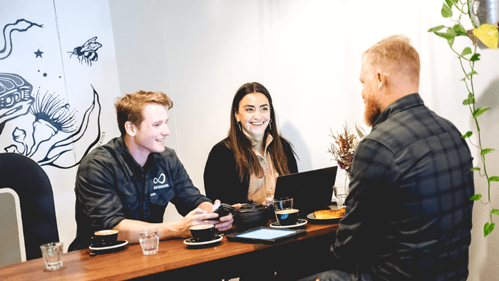 young male and female sitting across from man drinking coffee