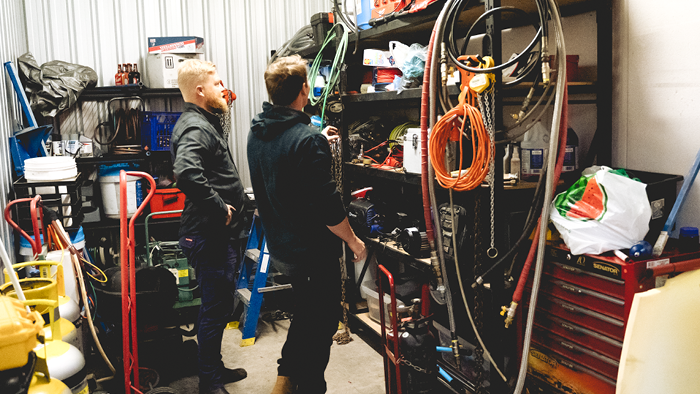 two men in tool shed looking at tools on shelves