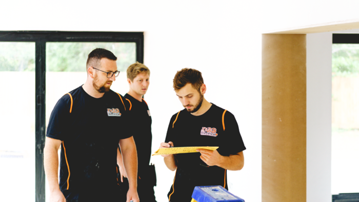 three tradies at worksite looking at work plans on paper