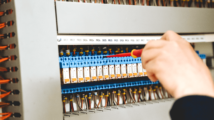 close up of hand with screw driver working on switch board plugs 