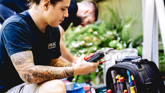 man looking at phone in hand while holding other tools