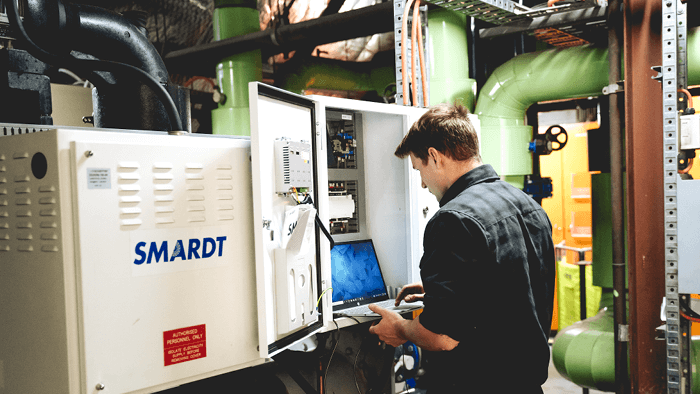 young HVAC technician standing in front of a large SMARDT unit