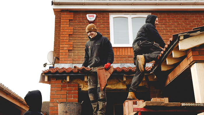 three tradies working on a house development site on top of the roof