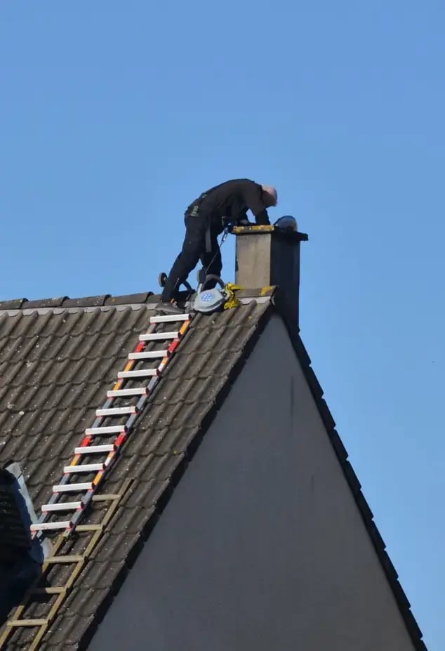 Man cleaning chimney from the roof