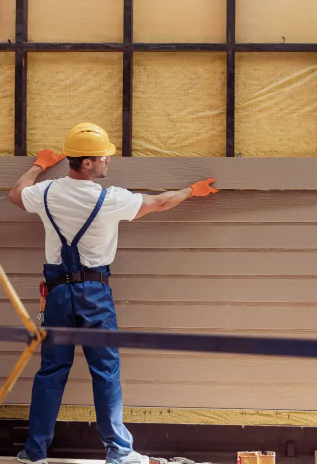 Man installing cladding on exterior of building