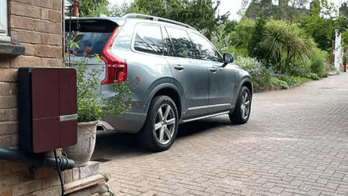 electrical car parked in a driveway with charging box fixed to a brick wall