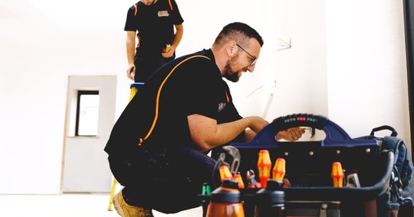 Electrician kneeling next to tool box-min