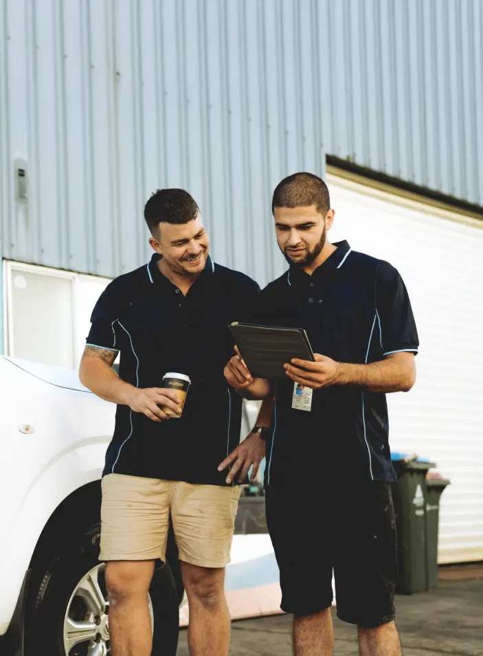 two tradespeople reviewing work on an ipad