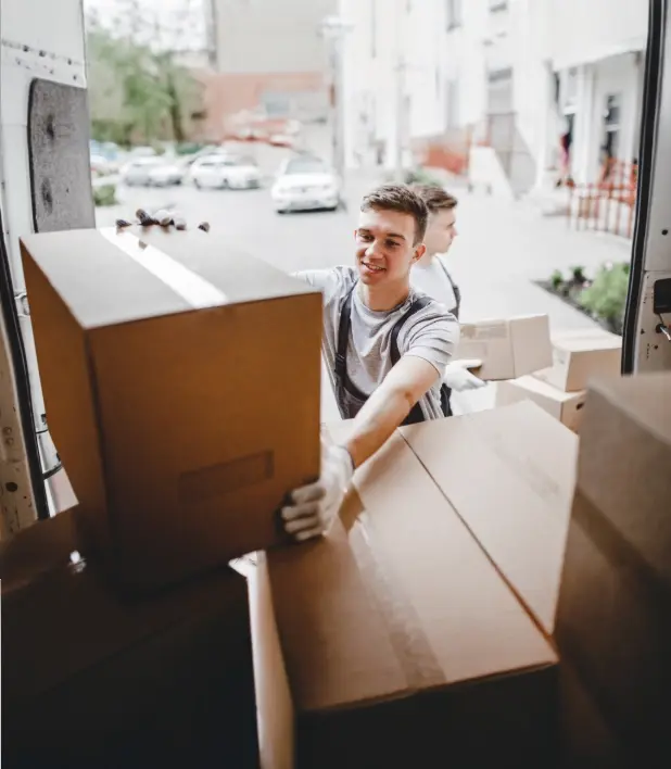A young man moving a box at the back of a moving truck 