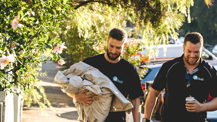 two men walking with gardening tools in hand