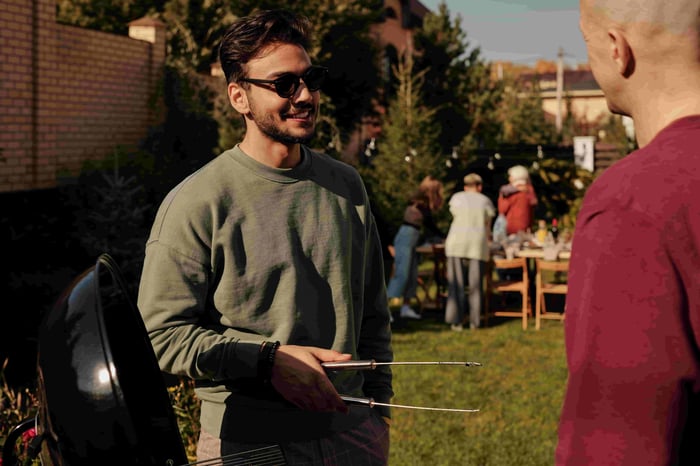 Two men standing at barbecue talking