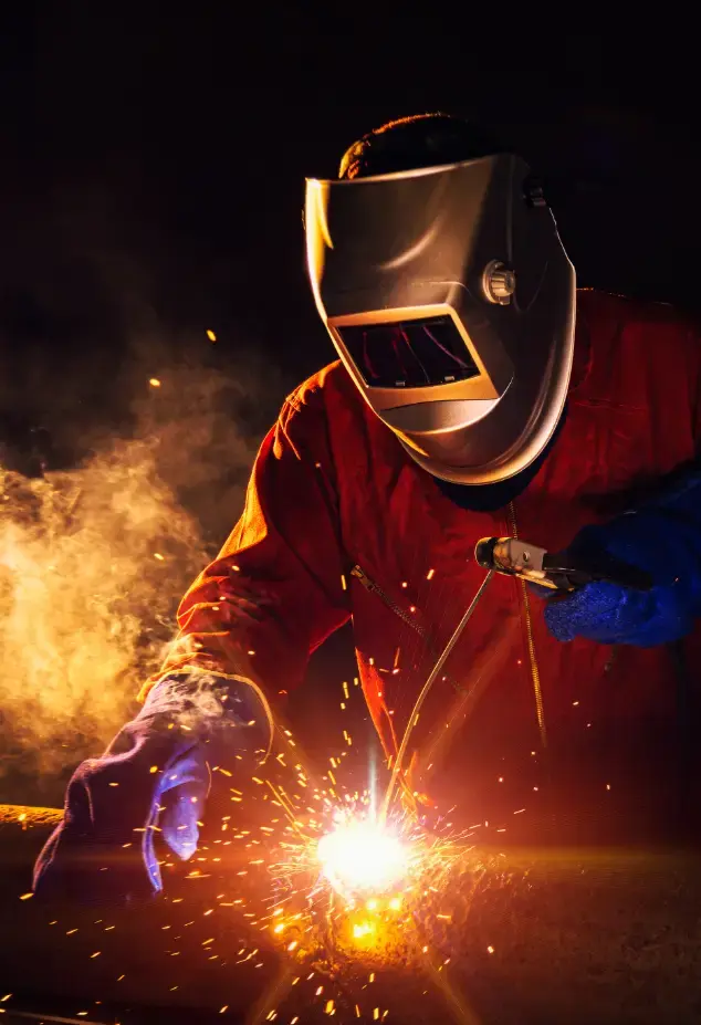 Welder in protective gear working on a pipe